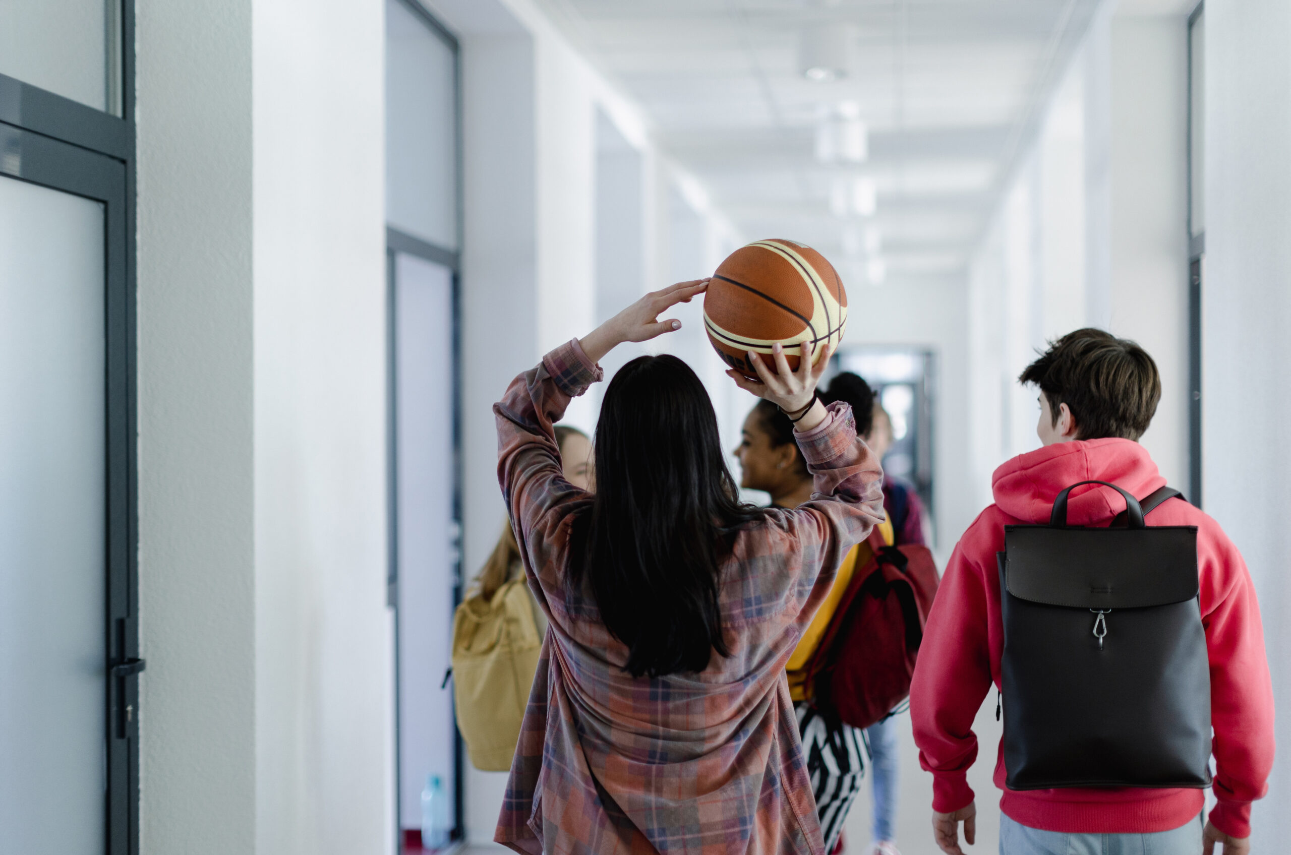 A rear view of young high school students walking in corridor at school, back to school concept.