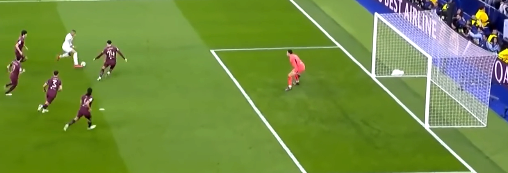 mbappe_pre_move A soccer player in white is preparing to shoot at goal, facing a goalkeeper in orange, with several defenders in dark jerseys nearby.